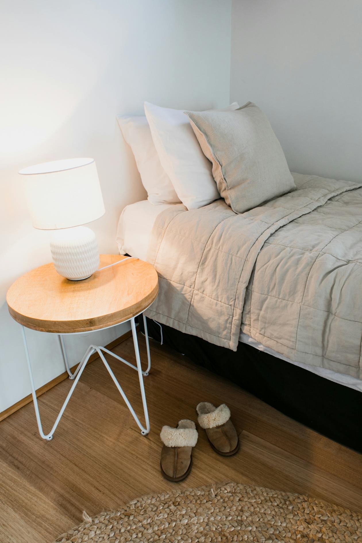 Cozy bedroom corner with warm glowing lamp and soft bedding